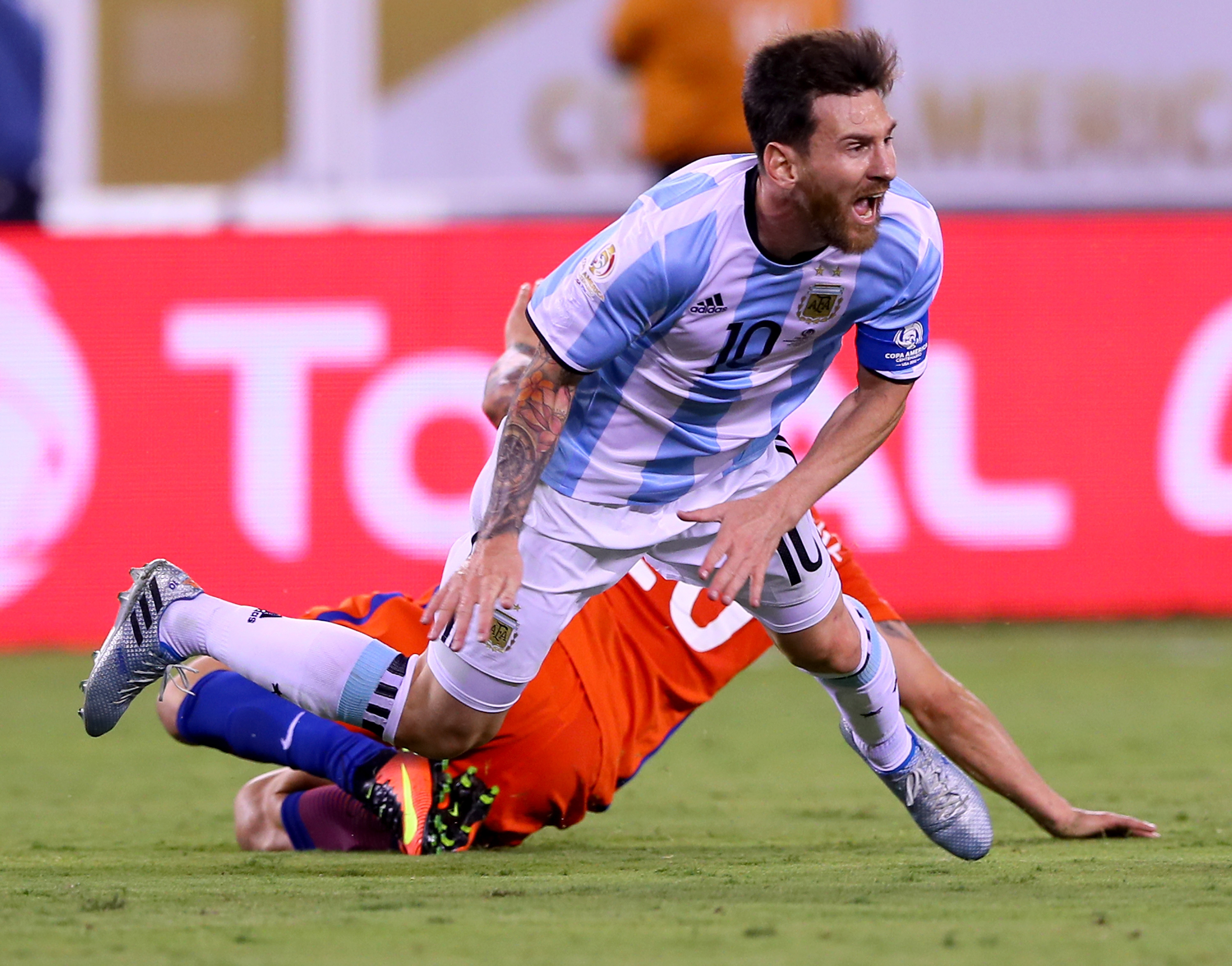 Lionel Messi of Argentina is tripped up by Charles Aranguiz of Chile. Photo / Getty Images.