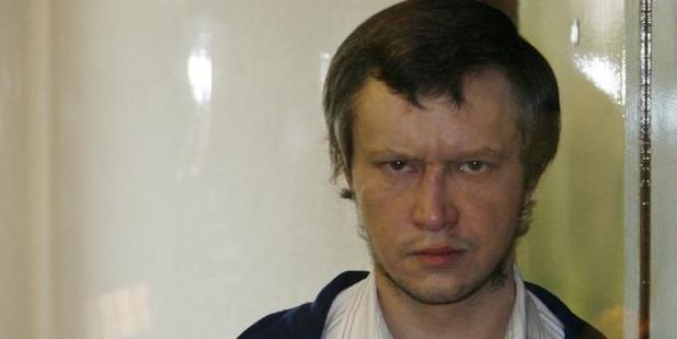 Alexander Pichushkin looks on from behind a glass security cage during the first day of his trial in Moscow in 2007. Photo / AP