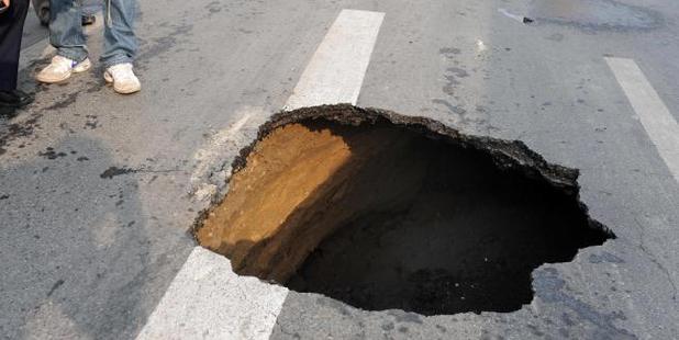 Chinese workers inspect a sinkhole that appeared in a Beijing street on February 8, 2010. Photo / AFP