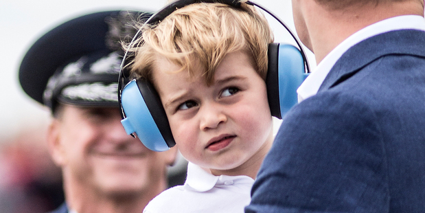 Prince George, wears earmuffs against the roar of aircraft as he visits with his father Prince William. Photo / AP