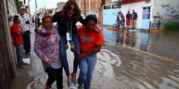 'Lady Reportera' is carried through floodwaters in Puebla, Mexico. Photo / Twitter / @BuzzfeedMexico
