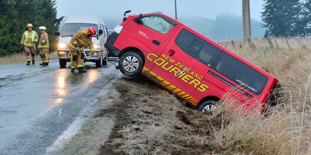 Outram volunteer firefighters clear the Henley - Berwick Rd after a courier van left the road after striking black ice this morning. Photo / Gerard O'Brien