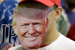AJ Garrett holds a mask of Republican presidential candidate Donald Trump before a rally in Westfield, Indiana. Photo / AP