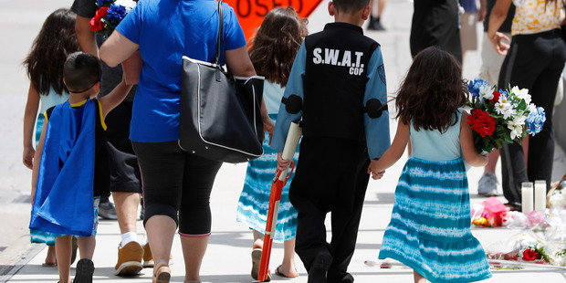 Victor Gutierrez wears a Swat outfit as he joins his family in delivering flowers to a memorial in Dallas, Texas. Photo / AP