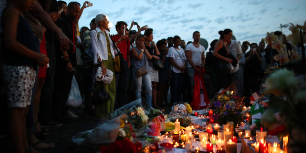 People gather around flowers placed on the Promenade des Anglais. Photo / Getty