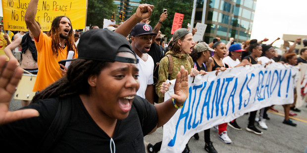 Black Lives Matter protesters march through Atlanta this week. An Emmy-winning US news producer has been fired for offensive online posts calling for the protesters to be bombed. Photo / AP