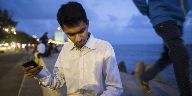 Vishal Agrawal listens to foreign exchange rates using his mobile phone on the waterfront at Nariman Point in Mumbai, India. Photo / Bloomberg, Prashanth Vishwanathan