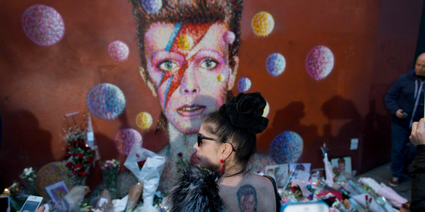 A woman with a Bowie tattoo on her back looks at a mural of the singer in Brixton, south London. Photo / AP