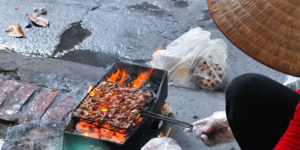 A woman cooks barbecue meat on the streets of Hanoi in Vietnam. Photo / 123RF