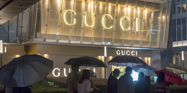 Pedestrians holding umbrellas walk past a Gucci luxury goods store in Shanghai in October. Photo / Bloomberg