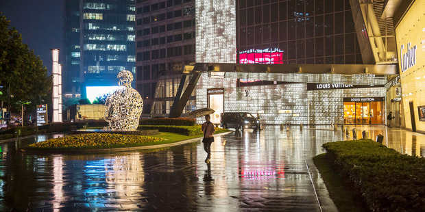 A pedestrian holding an umbrella walks past a Louis Vuitton store in Shanghai in October. Photo / Bloomberg