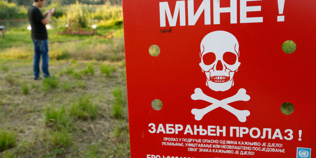 A Bosnian man plays the Pokemon game on his phone near a sign warning of a minefield. Photo / AP