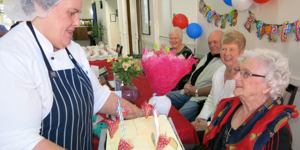 BIRTHDAY BASH: Country Lodge assistant cook Roz Kurzfeld delivers a cake with 103 spelt out in candles for Mrs Forbes.