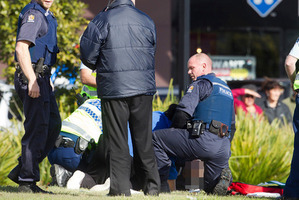 Police tend to the wounded man. Photo / Ben Fraser
