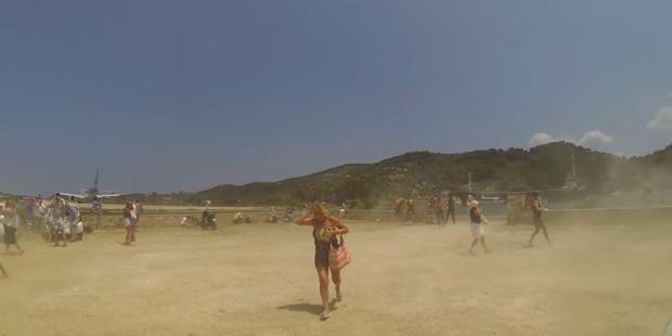 Tourists ran for cover as the jet sent clouds of sand billowing. Photo / YouTube, Cargospotter