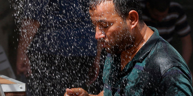 An Iraqi man cools off the summer heat by using an open air shower in Baghdad. Photo / AP