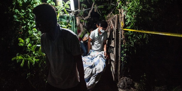 Forensic workers take out the body of an alleged drug dealer killed in a shootout with police during a drug raid. Photo / Getty Images