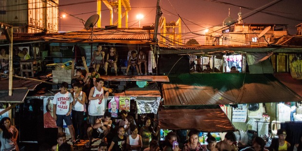 People living in a shanty community look on at a crime scene. Photo / Getty Images