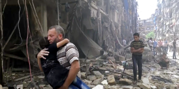 A man carries a child after airstrikes hit Aleppo in Syria. Photo / AP