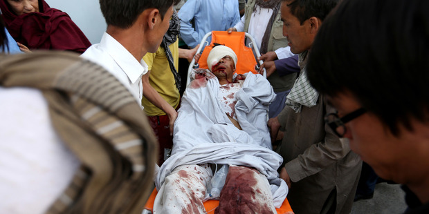 Afghans help a man who was injured in a deadly explosion that struck a protest march by ethnic Hazaras, in Kabul. Photo / AP