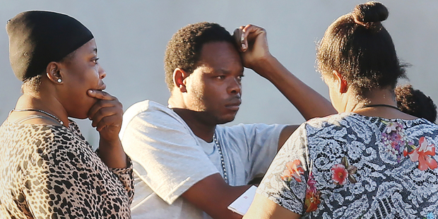 Jean Archilles, center, father of Sean Archilles, speaks with Fort Myers Police victim advocate Chevala Jones, right, after a fatal shooting at Club Blu. Photo / AP