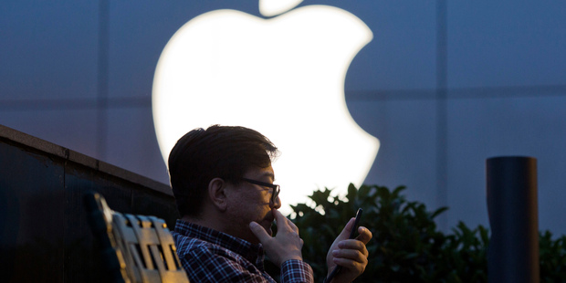 A man uses his mobile phone near an Apple store in Beijing. Apple sold 40.4 million iPhones in the last quarter - 15 percent fewer than a year ago Photo / AP