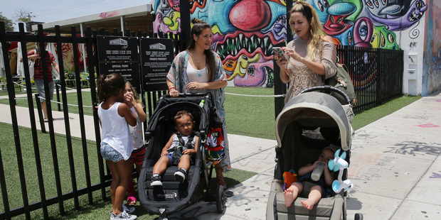 Vanessa Gomez, 33, left, with her son Ezra, 2, and her friend Cristy Fernandez, 33, with her 9-month-old- son River, of Miami, walk in the Wynwood neighborhood of Miami. Photo / AP