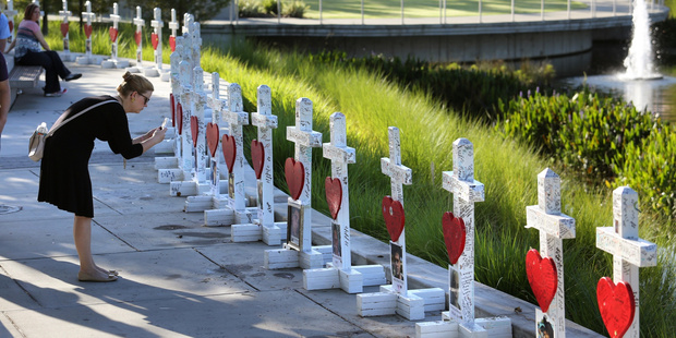 On the one-month anniversary of the Pulse nightclub massacre, Orlando Regional Medical Center employee Amanda Jane Saunders-Johnston takes a look at crosses honoring the 49 victims. Photo / AP