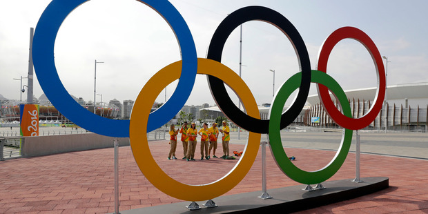 Volunteers stand near a set of Olympic Rings at Olympic Park in Rio de Janeiro. Photo / AP