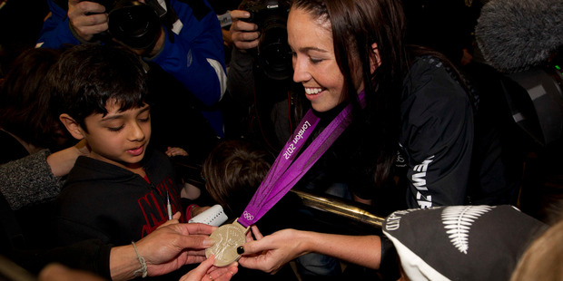 Sarah Walker shows of her Olympic medal to fans at Auckland International Airport. Photo / Steven McNicholl