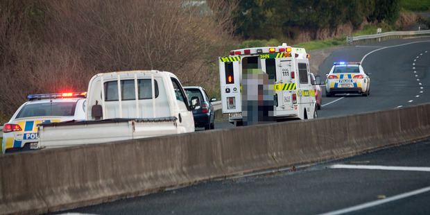 Emergency services treat a woman at the scene of a crash where three people changing a tyre were hit by a car. Photo/Andrew Warner