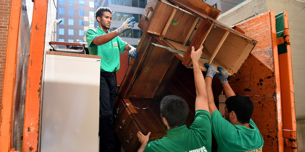 Left to right: Daniel McLeod, Alex Abramson and Patrick Bernardo of College Hunks Hauling Junk and College Hunks Moving remove furniture at the National Council of English Teachers office in Washington. Photo / Matt McClain