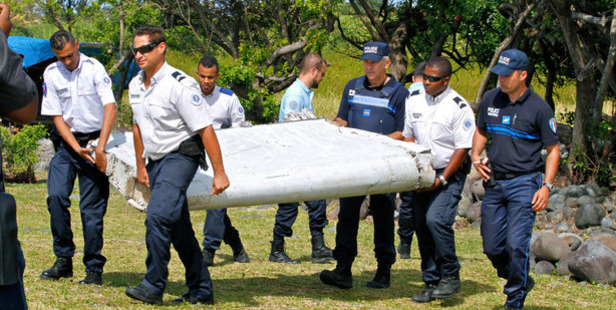 French police officers carry a washed-up piece of airplane debris found in July on a remote island in the Indian Ocean as part of Malaysia Airlines Flight 370. Photo / AP