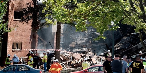 Fire and rescue crews and investigators are seen at the site of an overnight explosion and fire that destroyed an apartment building in the Flower Branch Apartments complex. Photo / AFP
