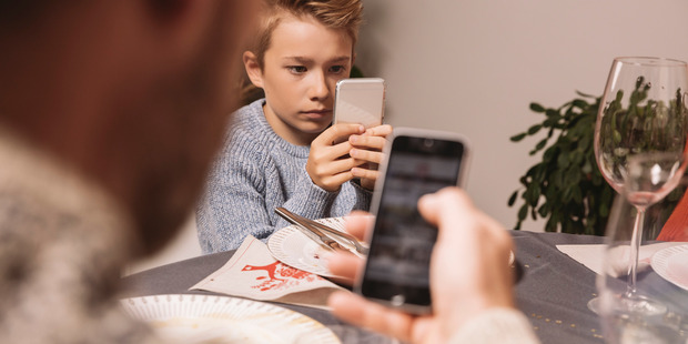 Common Sense suggests that families worried about the effect of screens on their relationships try putting away devices at dinner. Photo / Getty Images