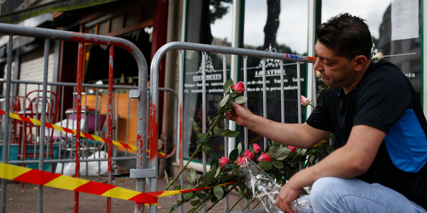 A man places a rose outside the bar where a fire broke in Rouen. Photo / AP