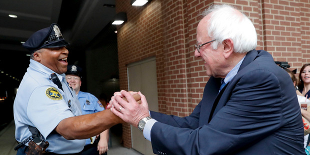 Sanders greets a police officer during walk around downtown in Philadelphia. Photo / AP