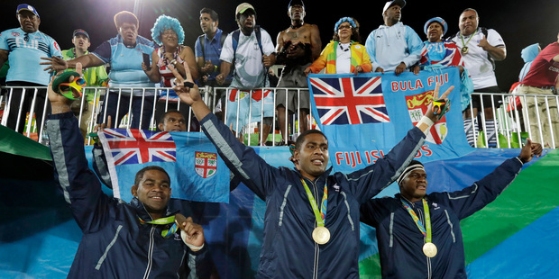 Vatemo Ravouvou, Viliame Mata, and Semi Kunatani, of Fiji, pose with fans after winning the gold medal match against Britain. Photo / AP.