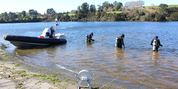 Police National Dive Squad divers enter Lake Arapuni from Arapuni Landing as part of a grid search of waterways around the missing woman's home.