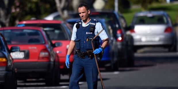 A police officer removes what appears to be a homemade spear gun from a property in Brookfield today. Photo/George Novak