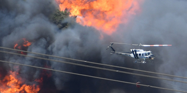 A helicopter flies near flames from the Bluecut Fire in San Bernardino, California. Photo / AP