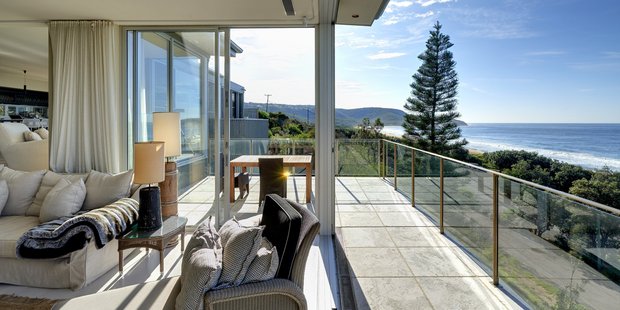 The lounge opens to a wrap-around balcony overlooking the coast. Photo / Supplied