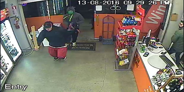 Two men, one carrying a length a wood, are shown in this CCTV still from a liquor store in Three Kings on Saturday night where two shop assistants were injured when attacked by the intruders.