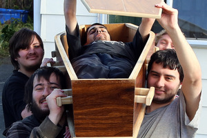 Jesse Hosie, Curtis Curry (front), Jeano Hosie (in coffin), Vaughn Holt and Jefferson Cameron-Kemp (rear) with the homemade coffin they are trying to sell on Facebook.