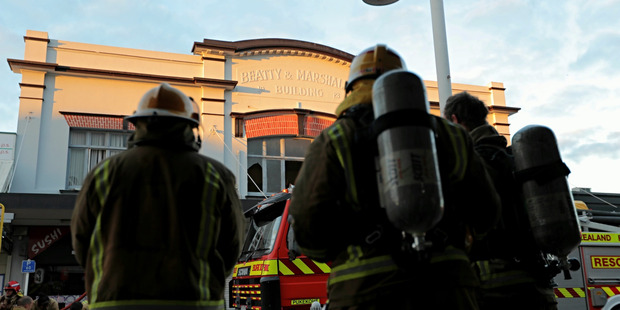 Firefighters survey the damage at this morning's arcade fire in Pukekohe. Photo / Michael Craig