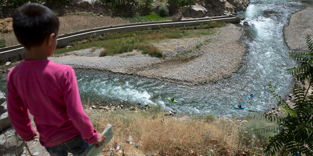 An Afghan schoolboy watches three foreign tourists kayaking along the Panjshir River. Photo / AP