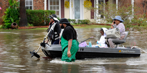 Volunteers pull a boat with a woman and young child as they evacuate from their homes. Photo / AP