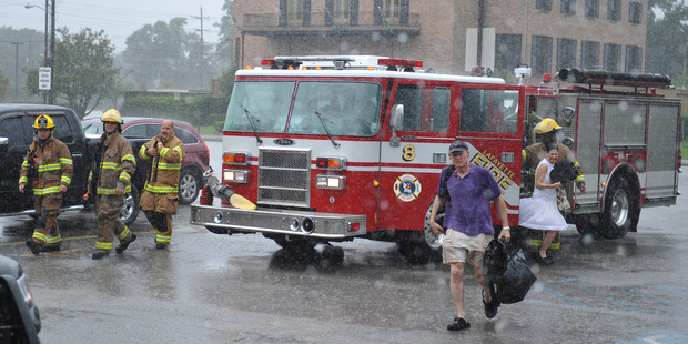 Lafayette firefighters bring people rescued from flood waters to the Heymann Performing Arts Center. Photo / AP
