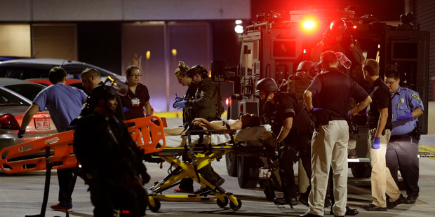 Under armed police personnel a young man is rushed into a hospital in Milwaukee. Photo / AP