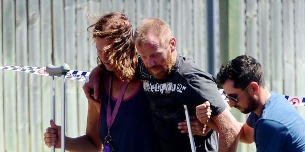 A man is walked back to the scene by fellow backpackers and a detective. Photo / News Corp Australia